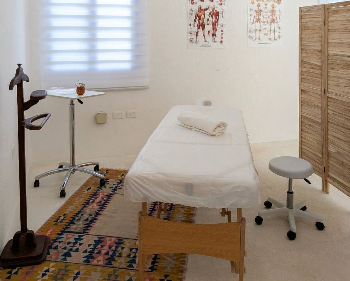 The treatment room: a massage table, anatomy charts on the wall, and a wooden folding screen